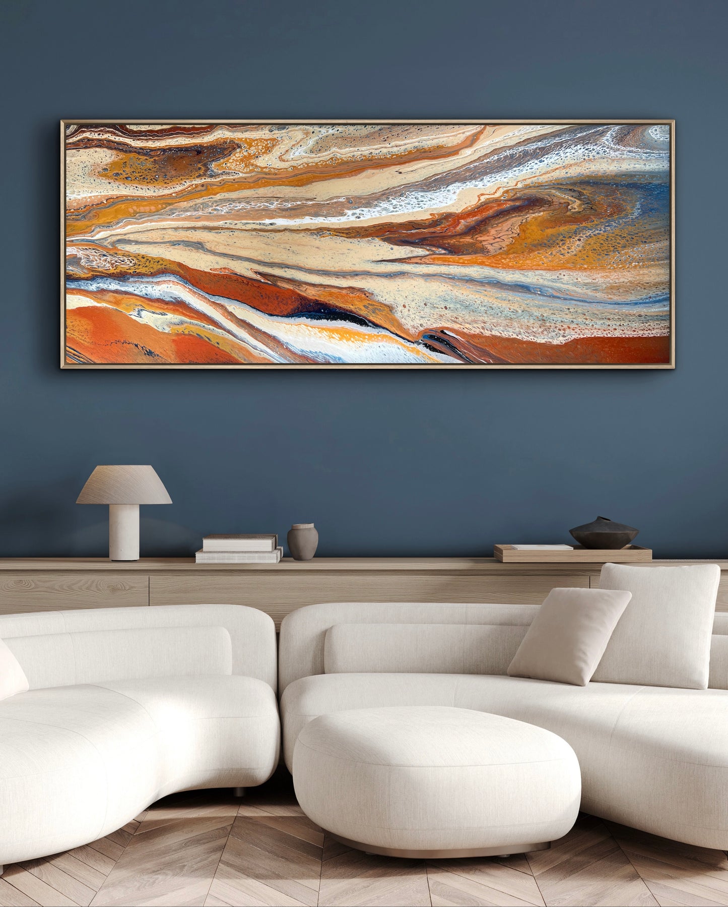 Desert Drift horizontal abstract painting displayed above a white sectional sofa against a deep blue wall