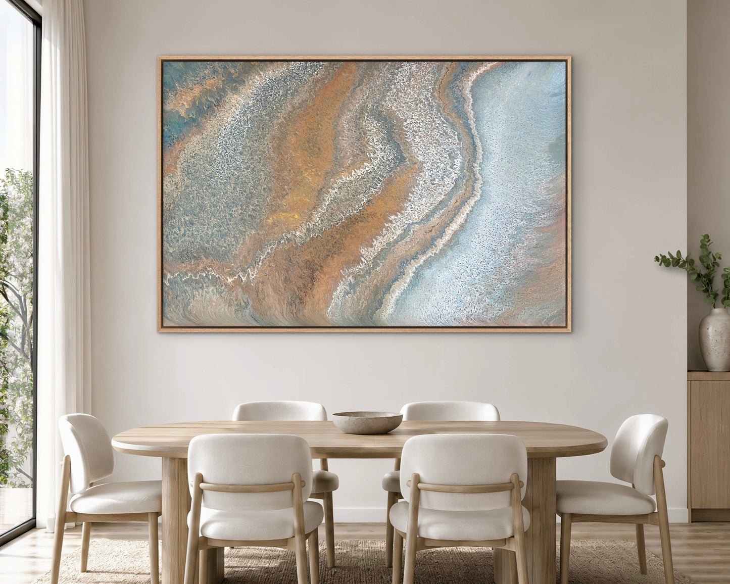 Weathered Tides large blue and ochre abstract landscape painting displayed above a round timber dining table in a bright contemporary interior
