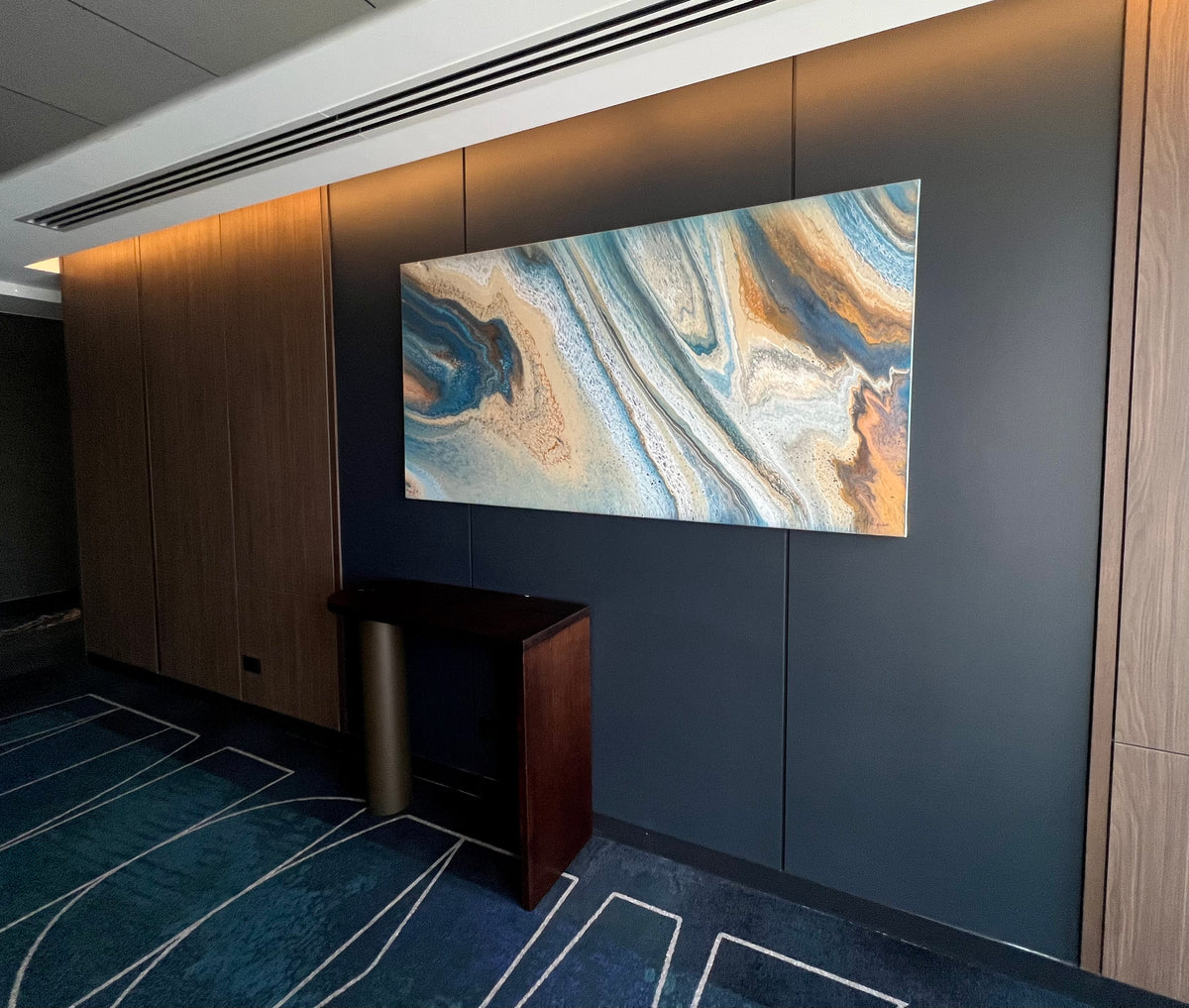 Large blue and ochre abstract painting by Angela Roskell installed opposite the lifts at Novotel Sydney Cabramatta
