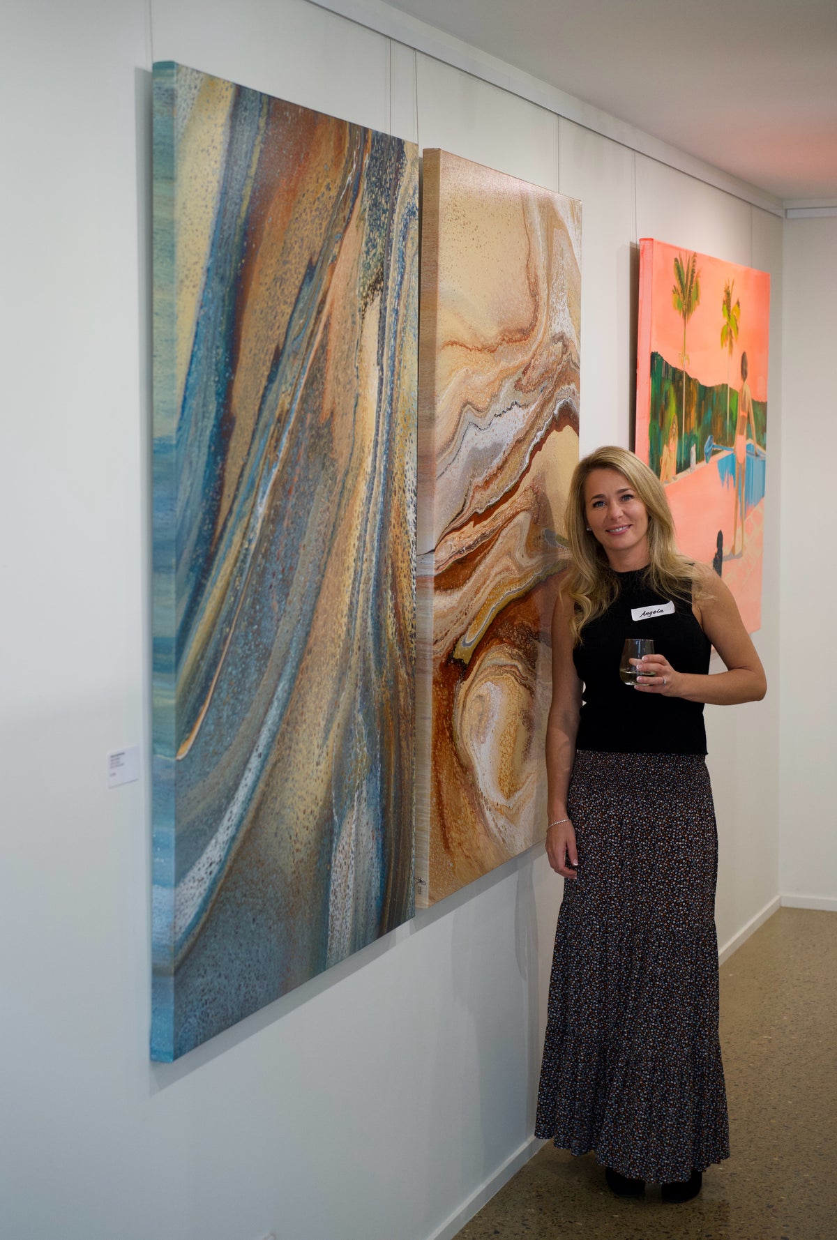 Australian abstract artist Angela Roskell standing beside her large original paintings at an Art Lovers Australia exhibition on the Gold Coast, QLD