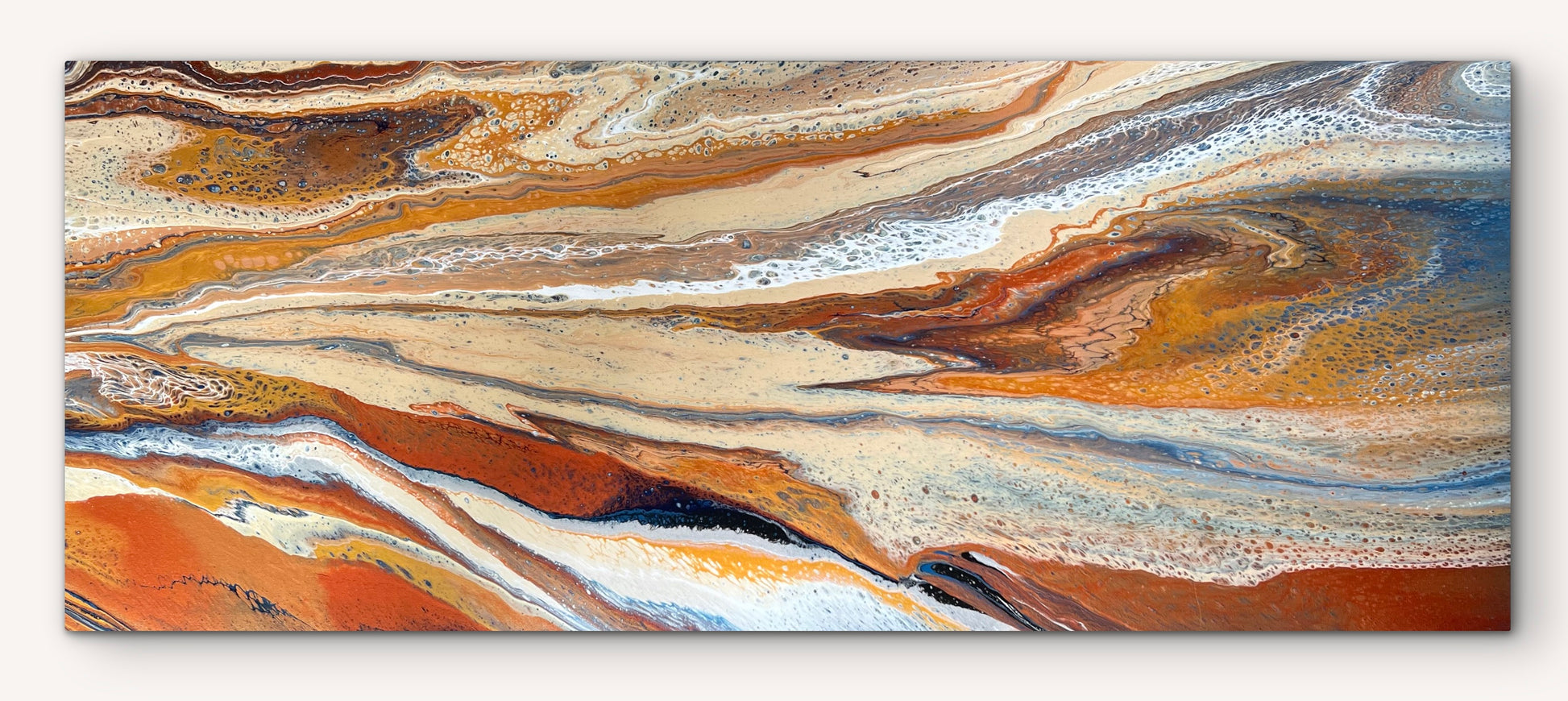 Full view of Desert Drift, a wide original abstract canvas in burnt orange, sand, cream and blue, shown unframed, stretched and ready to hang.
